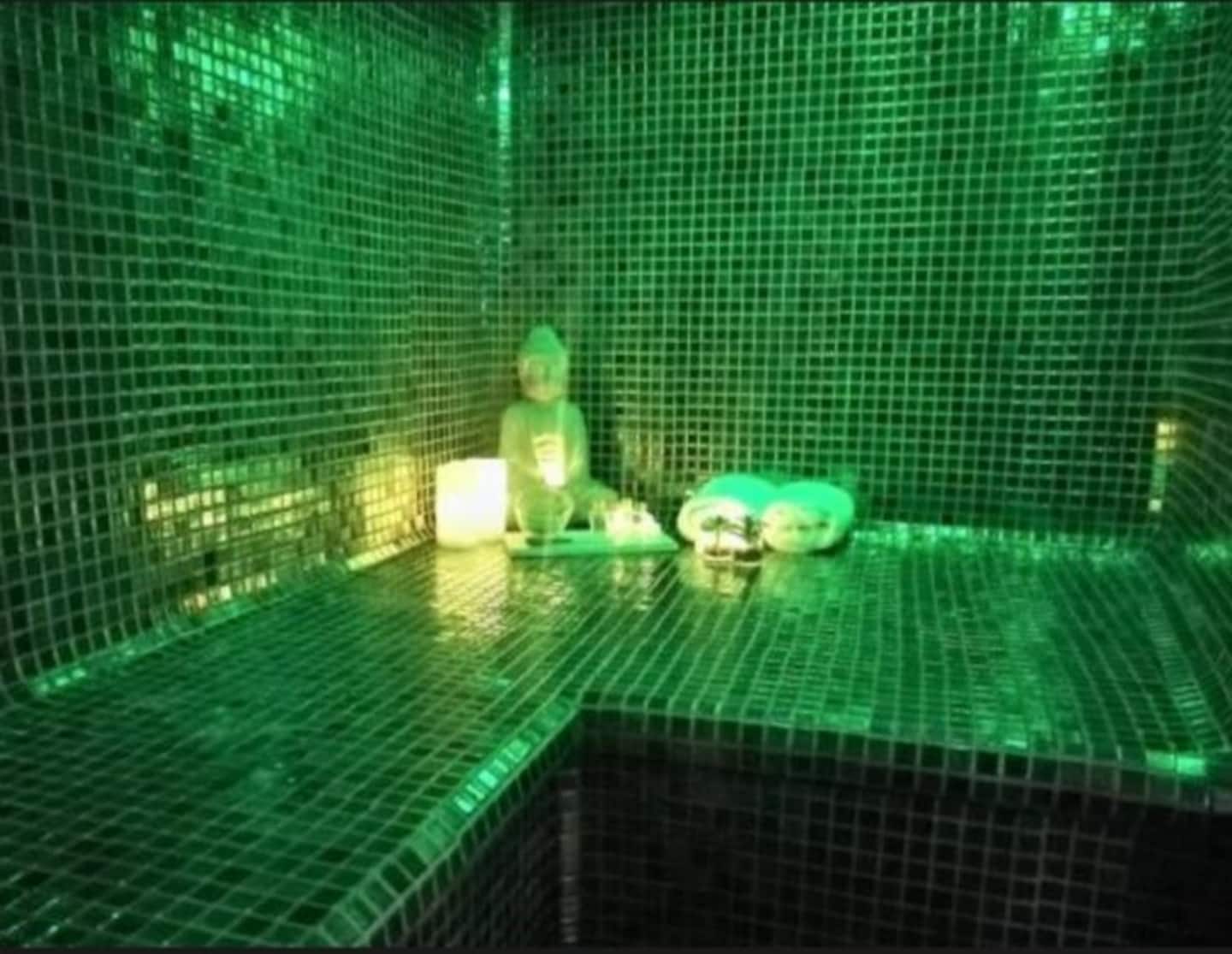 El baño turco privado, con mosaico verde y luz ambiental